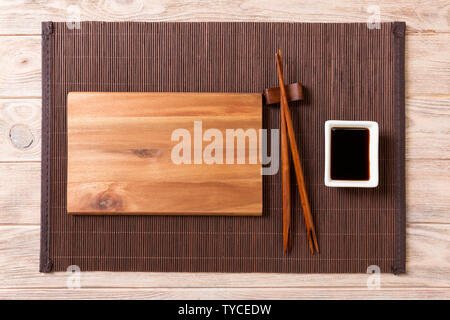 Empty rectangular wooden plate with chopsticks for sushi and soy sauce on wood background. Top view with copy space. Stock Photo