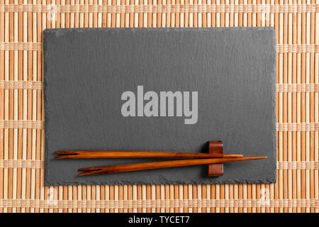 Empty rectangular black slate plate with chopsticks for sushi on wooden background. Top view with copy space. Stock Photo