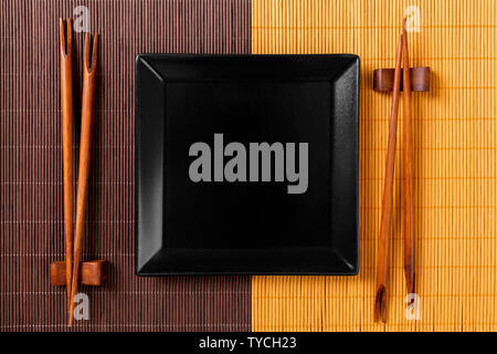 Empty black square slate plate with chopsticks for sushi on wooden background. Top view with copy space. Stock Photo