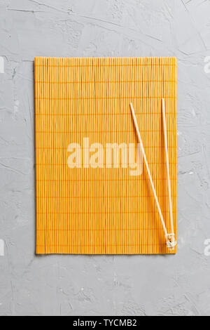 two sushi training sticks with empty bamboo mat or wood plate on stone Background Top view with copy stace. Stock Photo