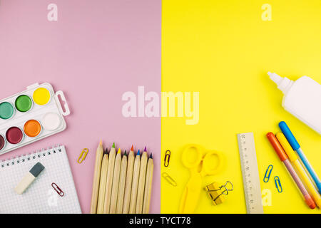 Different school supplies on pink and yellow paper background. Stock Photo