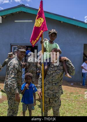 U.S. Marines Sgt. Wesley Davison, radio operator with Headquarters Platoon, and Cpl. Matthew Miller, combat engineer with Combat Engineer Platoon, Task Force Koa Moana 16-4, meet children at the kindergarten they renovated in Port Vila, Vanuatu, Nov. 1, 2016. During the closing ceremony, task force leadership and key leaders in the Vanuatu Police Force thank each other for their hard work, training and participation throughout their time together. Stock Photo