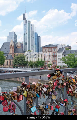 Frankfurt am Main, Germany - June 15 2019: Love locks adorn a bridge in Frankfurt with the city skyline in the background Stock Photo