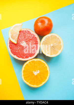 Flat lay of cut ripe juicy grapefruit, lemon and orange on yellow and blue background. Citrus pattern. Stock Photo