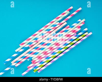 Background of Striped drink straws in different colors on blue Background. Stock Photo
