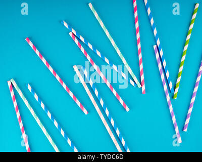 Background of Striped drink straws in different colors on blue Background. Stock Photo