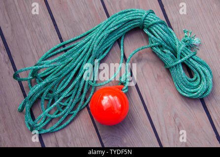 tackle to facilitate the supply of the mooring cable to the shore. A coil of thin green rope with a plastic red ball on the end. Stock Photo