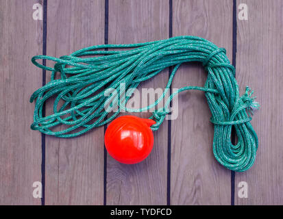 Sea tackle to facilitate the supply of the mooring cable to the shore. A coil of thin green rope with a plastic red ball on the end. Stock Photo