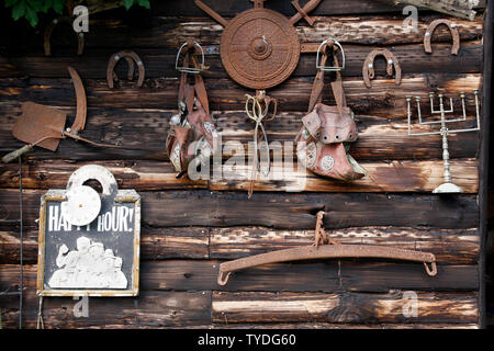 Rusty tools and ironware hanging on an old wooden barn wall Stock Photo