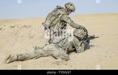 A squad leader with Charger Company, 1st Battalion, 77th Armored Regiment, 3rd Brigade, 1st Armored Division, checks his Soldier’s weapon during a squad live-fire exercise Nov. 2, 2016 at Udari Range near Camp Buehring, Kuwait. The four-day training exercise required Soldiers to tactically move as a squad, react to enemy contact, call for indirect fire, assault and clear a bunker and hastily assume defensive positions. Stock Photo