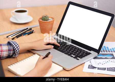 online learning course concept. student using computer laptop with white blank screen for training online and writing lecture note in notebook. distan Stock Photo