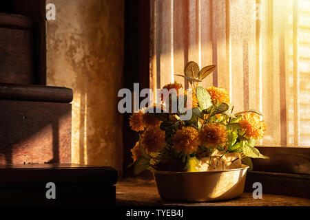 plastic flowers in old pots get sunlight from the side of the window. Stock Photo