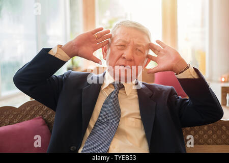 senior managing director business man suffering from headache from business work problem at office workplace. healthcare, pain, stress in elderly age Stock Photo