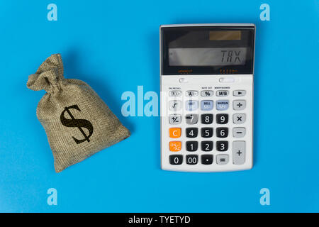 Business and finance taxes concept. A money bag and calculator with text on blue background from top view. Depicts the importance of management about Stock Photo