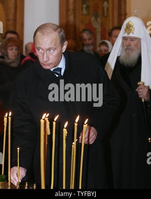 With Russian Orthodox Patriarch Alexiy II in the background President Vladimir Putin places a candle during a memorial service in Butovo, a site south of Moscow, on October 30, 2007. The Butovo firing range was used for executions from 1930 until after Stalin's death in 1953. Some 20,000 people, including priests and artists, were killed there in 1937-38 alone. (UPI Photo/Anatoli Zhdanov). Stock Photo