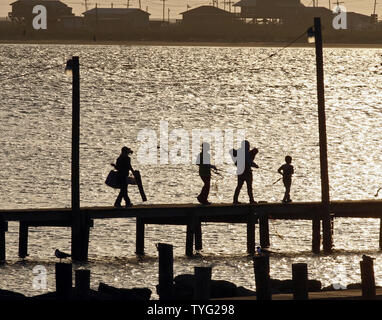 A family walks out a pier to fish at sunset on Grand Isle, Louisiana, April 18, 2011. Tourists and fishermen have begun to return to the island a year after the explosion of the Deepwater Horizon, which killed 11 men working on the platform and caused an underwater leak that gushed 53,000 barrels of oil a day for three months.  UPI/A.J. Sisco. Stock Photo