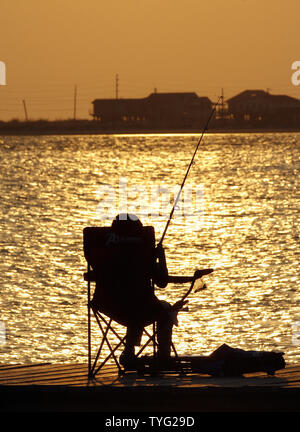 A child fishes at sunset on Grand Isle, Louisiana, April 18, 2011. Tourists and fishermen have begun to return to the island a year after the explosion of the Deepwater Horizon, which killed 11 men working on the platform and caused an underwater leak that gushed 53,000 barrels of oil a day for three months.  UPI/A.J. Sisco. Stock Photo