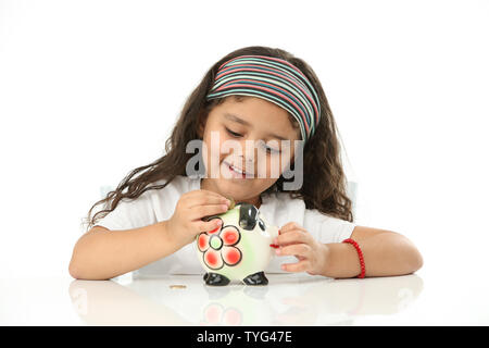 Indian girl putting coin into a piggy bank with her parents Stock Photo ...