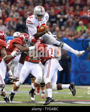 Ohio State quarterback Cardale Jones (12) leaps over Alabama defenders Nick Perry (27) and Geno Smith (24) for 18-yards and a first down during the first half of the Allstate Sugar Bowl playoff semifinal college football game at the Mercedes-Benz Superdome in New Orleans, Louisiana on January 1, 2015. Photo by David Tulis/UPI Stock Photo