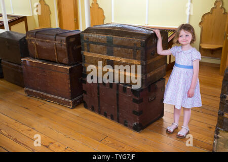 Girl / kid / child aged four years old, standing by a collection of luggage cases, trunks and suitcases on the first class promenade saloon deck / passenger deck of the SS Great Britain, Brunel's steam powered ship in dry dock, now a museum attraction in Bristol, UK (109). Stock Photo