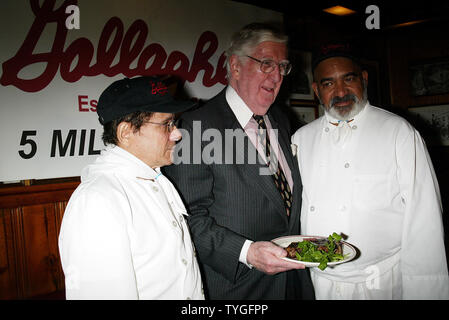 Michael Gillespie, a real estate developer from Manhattan, eats the 5 millionth steak served at Gallagher's Steak House in New York on January 14, 2004. Gillespie is a regular at Gallagher's, dining at the restaurant weekly for the past 40 years.  He received a bottle of Dom Perignon champagne with his lunch and will receive an annual dinner for two at Gallagher's for the next 76 years (in honor of the restaurant's 76 years in business).  Gillespie poses with the broiler cooks Johnny Muriel (right) and Jorge Rodriguez (left), both have worked at Gallagher's since the 1960's. Stock Photo