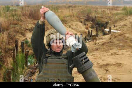 YAVORIV, Ukraine—A Ukrainian Soldier assigned to 1st Battalion, 80th Airmobile Brigade loads a 120mm round into a mortar system, Nov. 9, before a direct lay training live-fire exercise at the International Peacekeeping and Security Center. The training exercise was observed/controlled by Soldiers assigned to 6th Squadron, 8th Cavalry Regiment, 2nd Infantry Brigade Combat Team, 3rd Infantry Division, along with Polish and Ukrainian instructors, as part of the Joint Multinational Training Group-Ukraine. JMTG-U’s mission is aimed at developing defensive skills and improving Ukraine’s capacity for Stock Photo