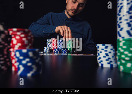 Successful man poker player counting his chips seated at the casino table. Gambling tournament winner concept. Stock Photo