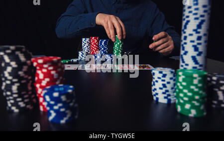 Successful man poker player counting money and betting chips seated at the casino table. Gambling tournament winner concept. Stock Photo