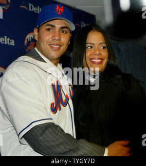 Carlos Beltran,center, tries on his new jersey as he is joined by New York  Mets' general manager Omar Minaya and his wife Jessica during a press  conferance where Beltran is announced as