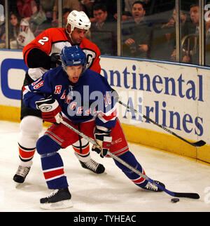 New York Rangers (18) Dominic Moore battles for control of the puck with Philadelphia Flyers (2) Derian Hatcher at Madison Square Garden in New York City on April 4, 2006. The New York Rangers defeated the Philadelphia Flyers 3-2 in an overtime Shoot out.    (UPI Photo/John Angelillo) Stock Photo