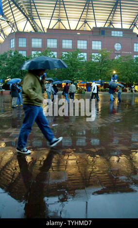 People arrive for the night session matches as the lights of the Arthur Ashe stadium reflect off off the wet pavement while the rain again postpones play at the US Open held at the USTA Billie Jean King National Tennis Center on September 5, 2006 in New York. (UPI Photo/Monika Graff) Stock Photo