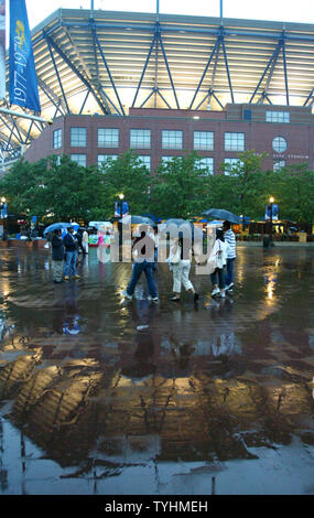 People arrive for the night session matches as the lights of the Arthur Ashe stadium reflect off the wet pavement while the rain again postpones play at the US Open held at the USTA Billie Jean King National Tennis Center on September 5, 2006 in New York. (UPI Photo/Monika Graff) Stock Photo