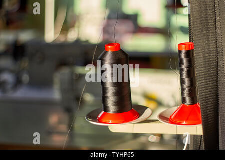 Spools of sewing threads. Black threads in the sewing workroom. Leathercraft. Stock Photo