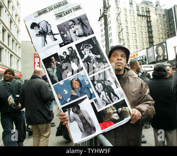 A man holds a collage of James Brown photos as he joins the thousands of fans lined up around the Apollo Theater to view the casket of singer James Brown in New York City on December 28, 2006. Brown died of congestive heart failure on December 25, 2006 and will be buried in his home town of Augusta, Georgia over the weekend. (UPI Photo/Monika Graff) Stock Photo