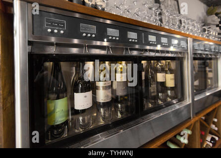 close up of wine bottles in dispenser at bar Stock Photo