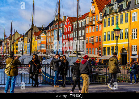 Tourists taking photos in Nyhavn, a 17th century canal and harbour area with bars and restaurants, in the capital city of Copenhagen, Denmark. 2019. Stock Photo