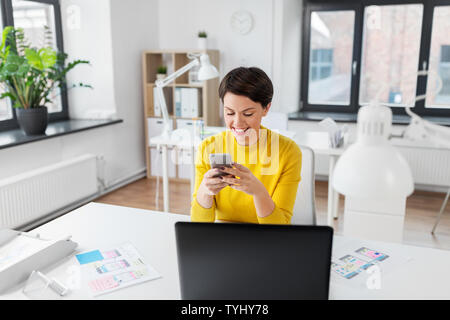 smiling ui designer using smartphone at office Stock Photo