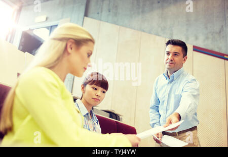 teacher giving exam tests to students at lecture Stock Photo