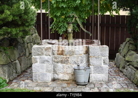 Stone well with water pump in the garden Stock Photo