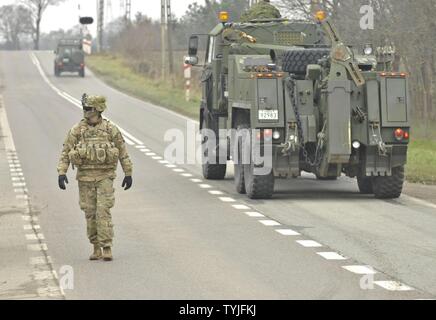 U.S. Army 1st Lt. Alexander G. Canacci, Paratrooper, Company D, 2nd Battalion, 503rd Infantry Regiment, 173rd Airborne Brigade, directs traffic during a Polish Independence Day parade involving his unit, Canadian soldiers assigned to 1st Battalion, Princess Patricia Canadian Light Infantry, and Polish soldiers (not pictured) throughout the township of Drawsko Pomorskie, Poland, Nov. 11, 2016. The Troops helped their Polish counterparts celebrate the country's national holiday that commemorates the anniversary of the restoration of Poland's sovereignty as the Second Polish Republic in 1918. Stock Photo