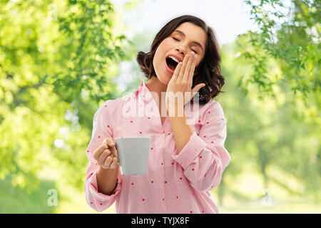 happy yawning young woman in pajama with coffee Stock Photo