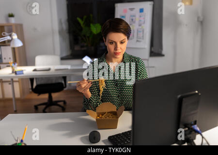 businesswoman eating and working at night office Stock Photo