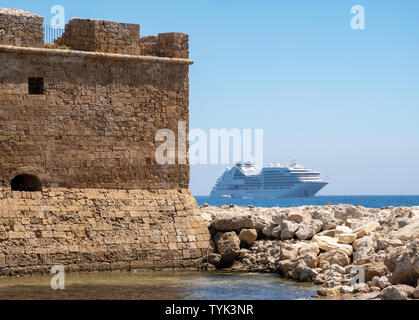 Paphos, Cyprus. A view of the Paphos Castle and the Seabourn Encore cruise liner anchored off the shore Stock Photo