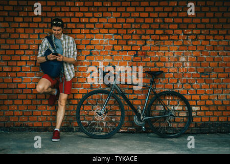 A young stylish man posing next to his bicycle. Stock Photo