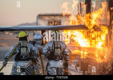 U.S. Marines with Aircraft Rescue and Firefighting (ARFF), Headquarters and Headquarters Squadron (H&HS), Marine Corps Air Station (MCAS) Yuma conduct hand line drills during live burn training on MCAS Yuma, Ariz., June 25, 2019. Hand line drills focus on techniques to push fuel fires away from aircraft, ARFF Marines train monthly to enhance their readiness when responding to emergencies on the flight line. (U.S. Marine Corps photo by Sgt. Allison Lotz) Stock Photo