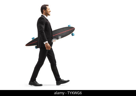 Full length profile shot of a businessman in a suit walking and holding a longboard isolated on white background Stock Photo