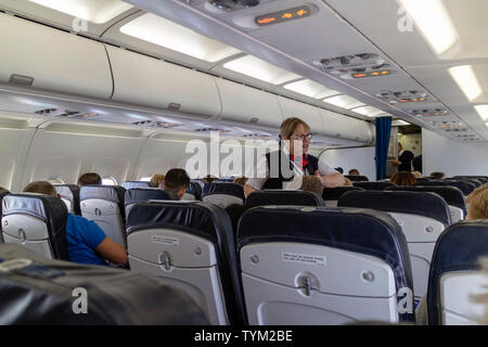 Inflight service on a passenger jet with crew member speaking to a passenger in club class aboard an A320 plane. Circa 2019. Stock Photo