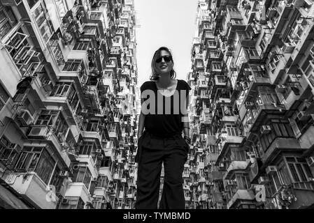 Woman in front of high-rise building with many units in Hong Kong Stock Photo