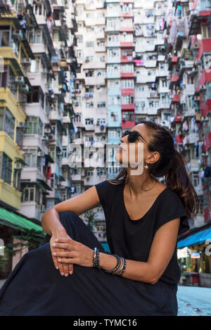 Woman in front of high-rise building with many units in Hong Kong Stock Photo