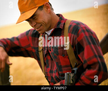 Man in plaid shirt leaning on post Stock Photo